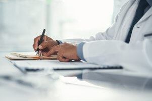 doctor writing on papers at desk