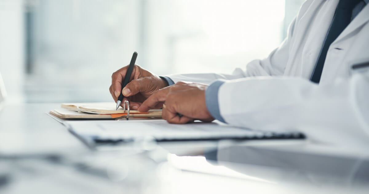 doctor writing on papers at desk