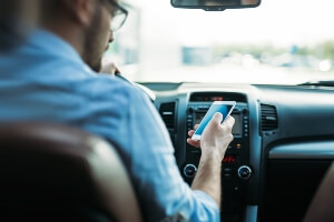 young male driver looking texting while driving