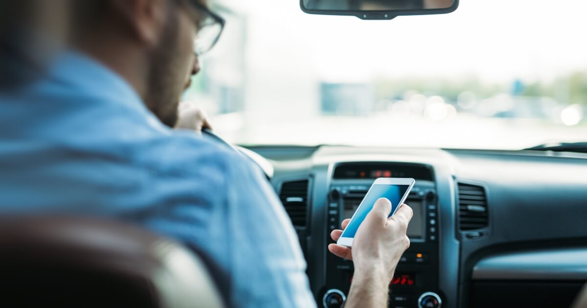 young male driver looking texting while driving